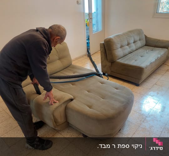 אדם מנקה ספה עם שואב אבק